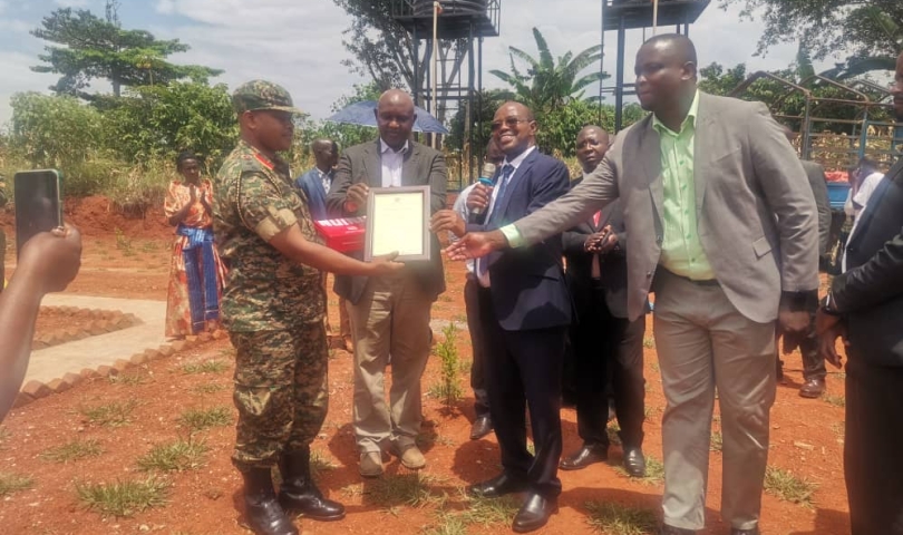 Honorable Minister and District leadership receiving a certificate of completion from the UPDF Engineering brigade